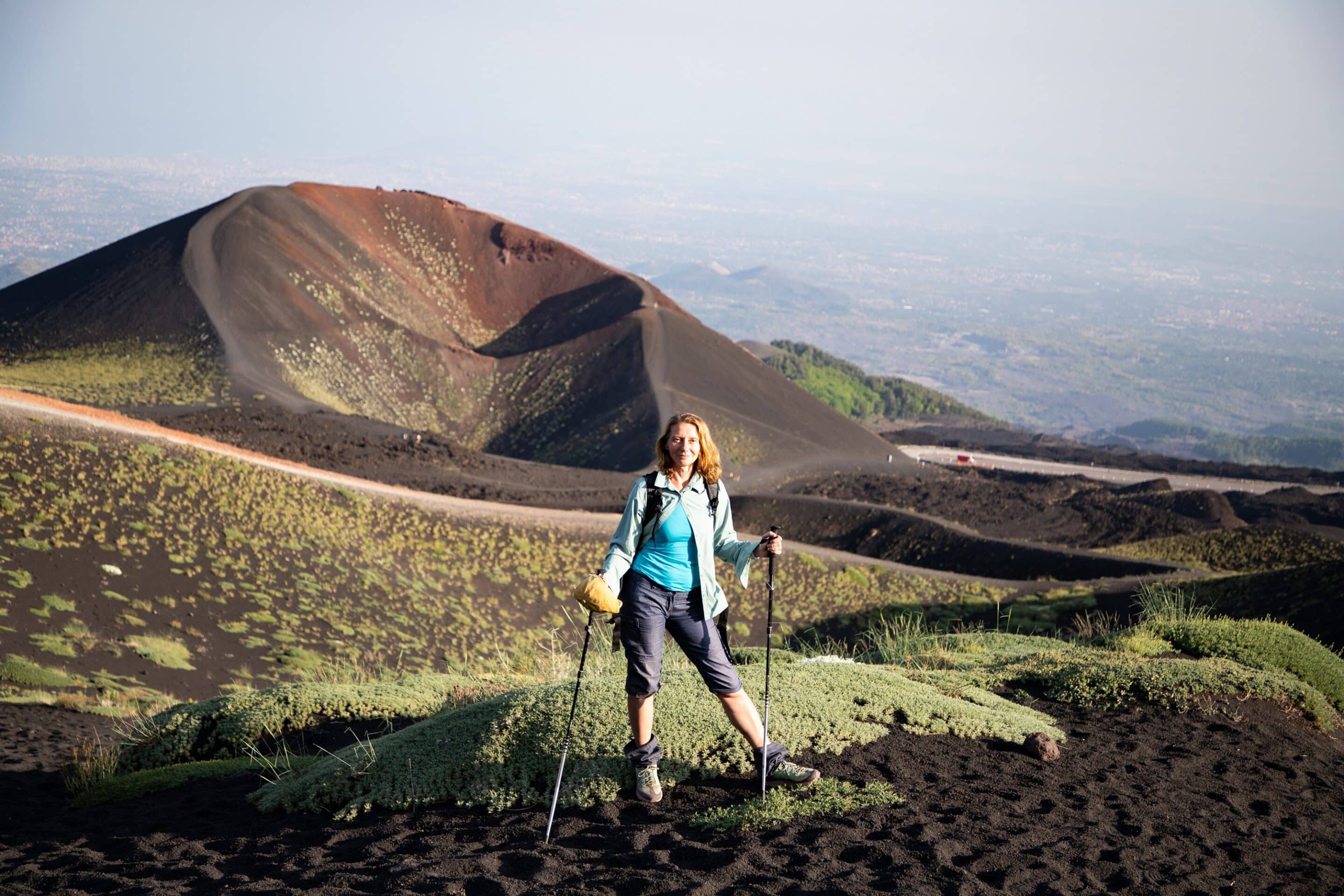 A hiker trekking along the dark volcanic ash slopes of Mount Etna in Sicily, Italy